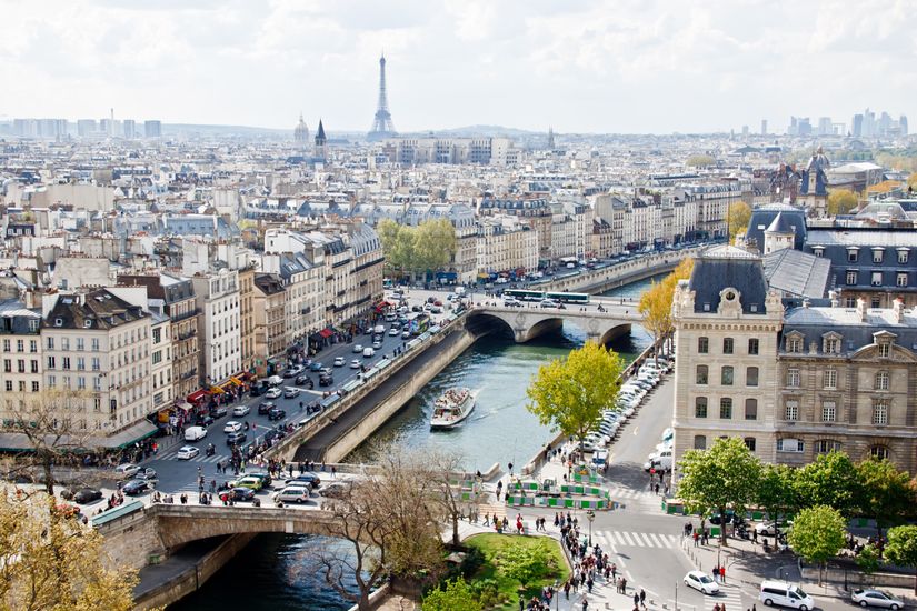 A daytime view of the Paris skyline from the top of Notre Dame looking out over the Seine River towards the Eiffel Tower