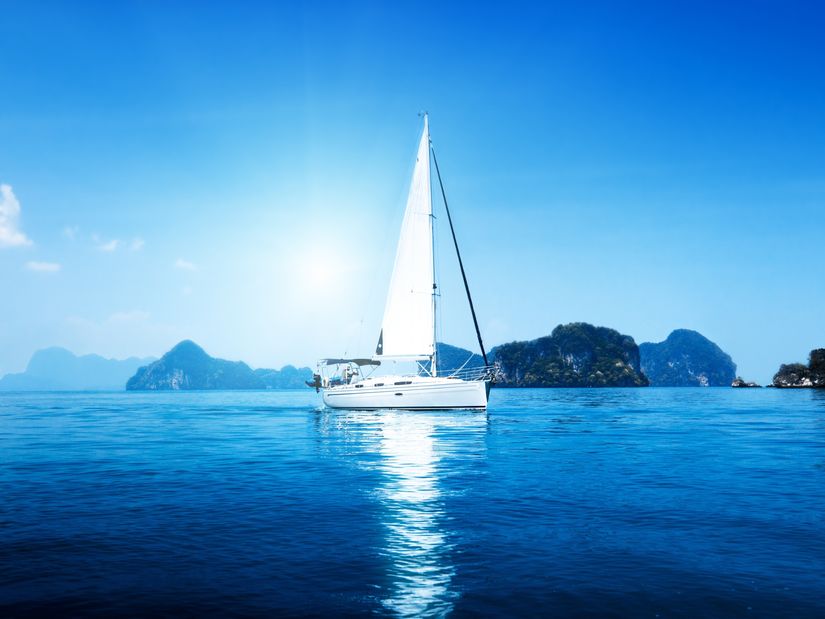 white-sailboat-sits-upon-calm-ocean-waters