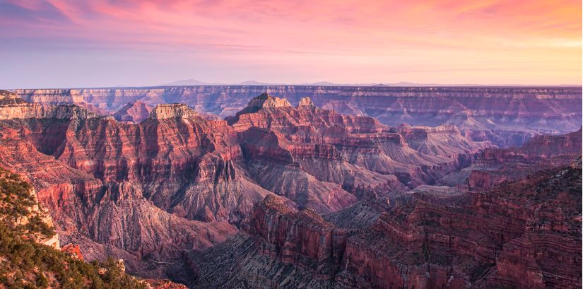 Panoramic-grand-canyon-horizon-landscape-at-sunset-or-sunrise-with-purple-and-pink-rock-formations