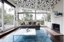 Living-room-with-sofa-table-and-a-black-and-white-geometric-pattern-mural-on-the-ceiling
