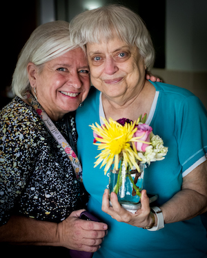 Two women holding a bouquet of flowers