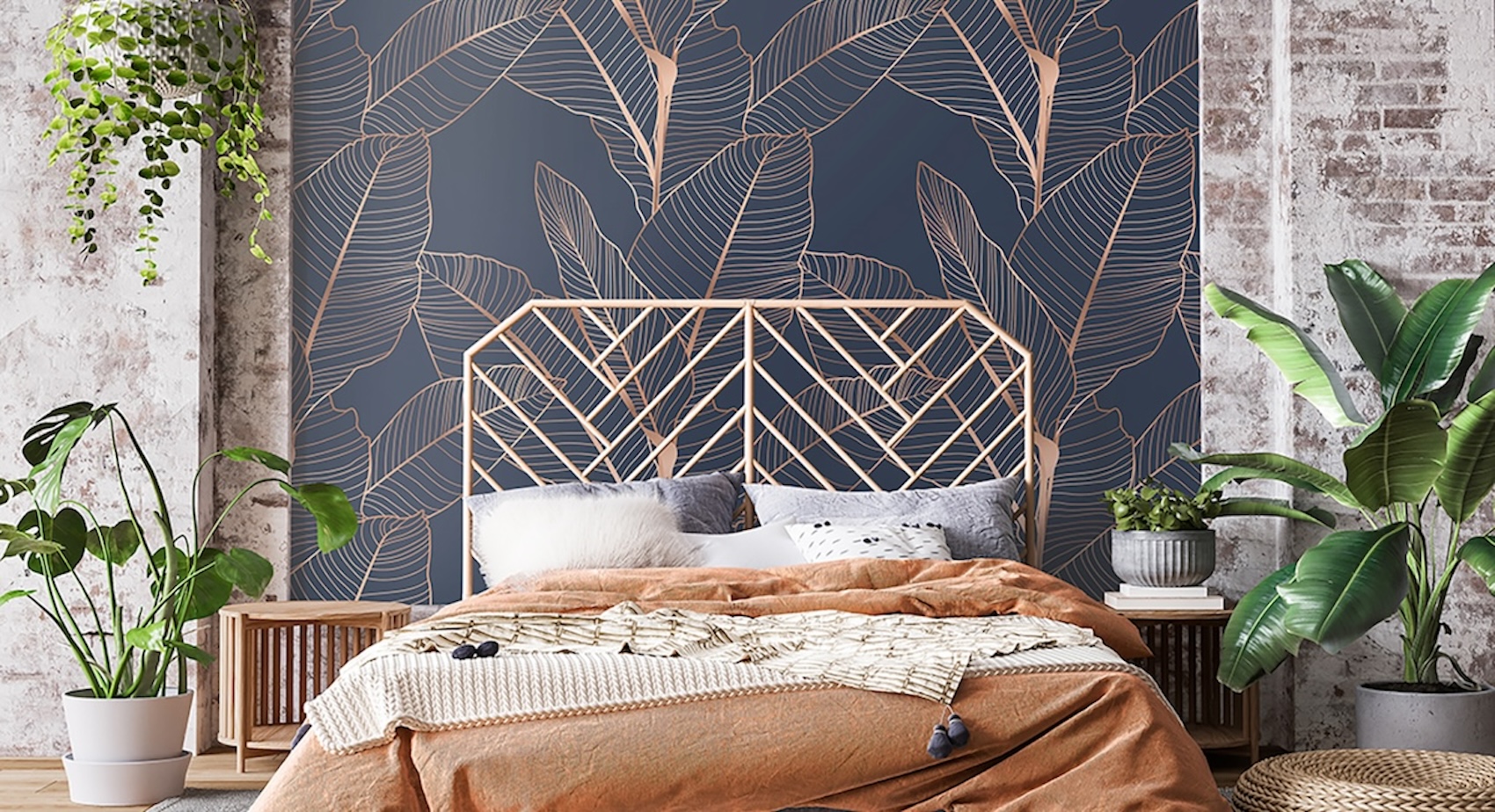 Mural of a banana leaf pattern in copper on blue behind a bed