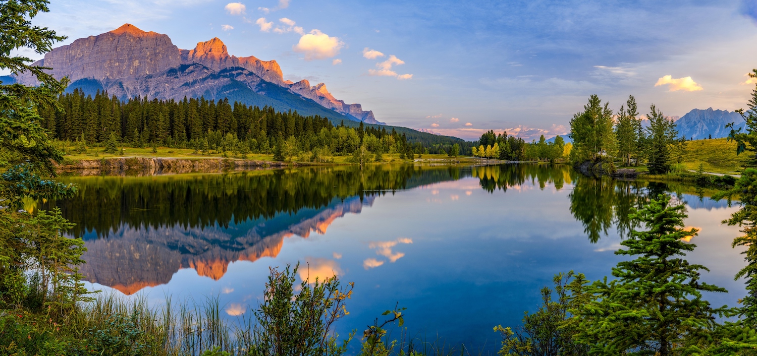 Mountains and forests are reflected in the still waters of a lake