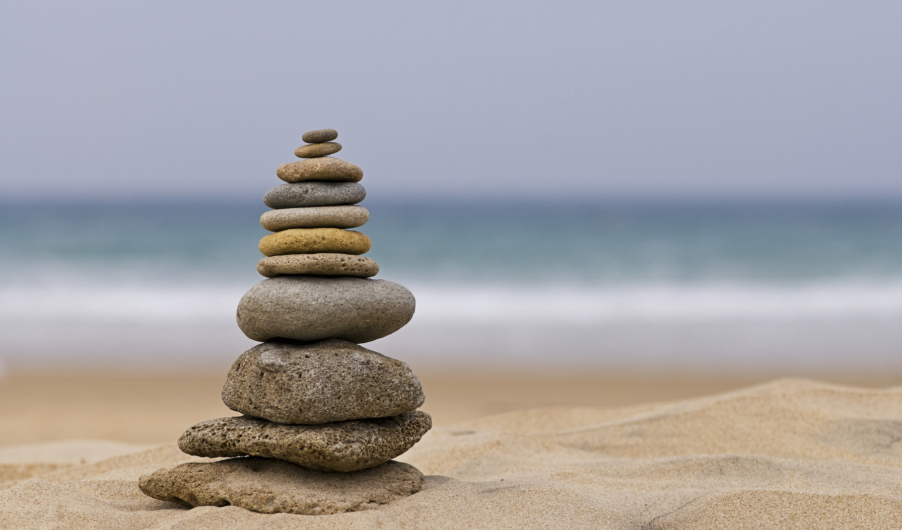 A stack of rocks from smallest to largest rest on a beach