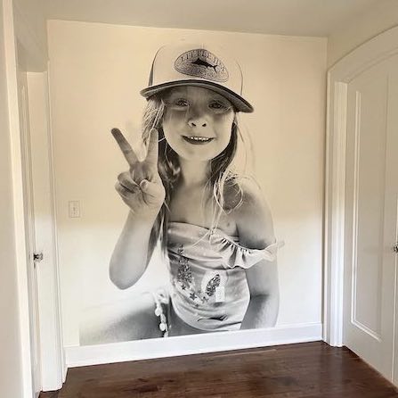 Black and white wall mural of a young girl holding up a peace sign