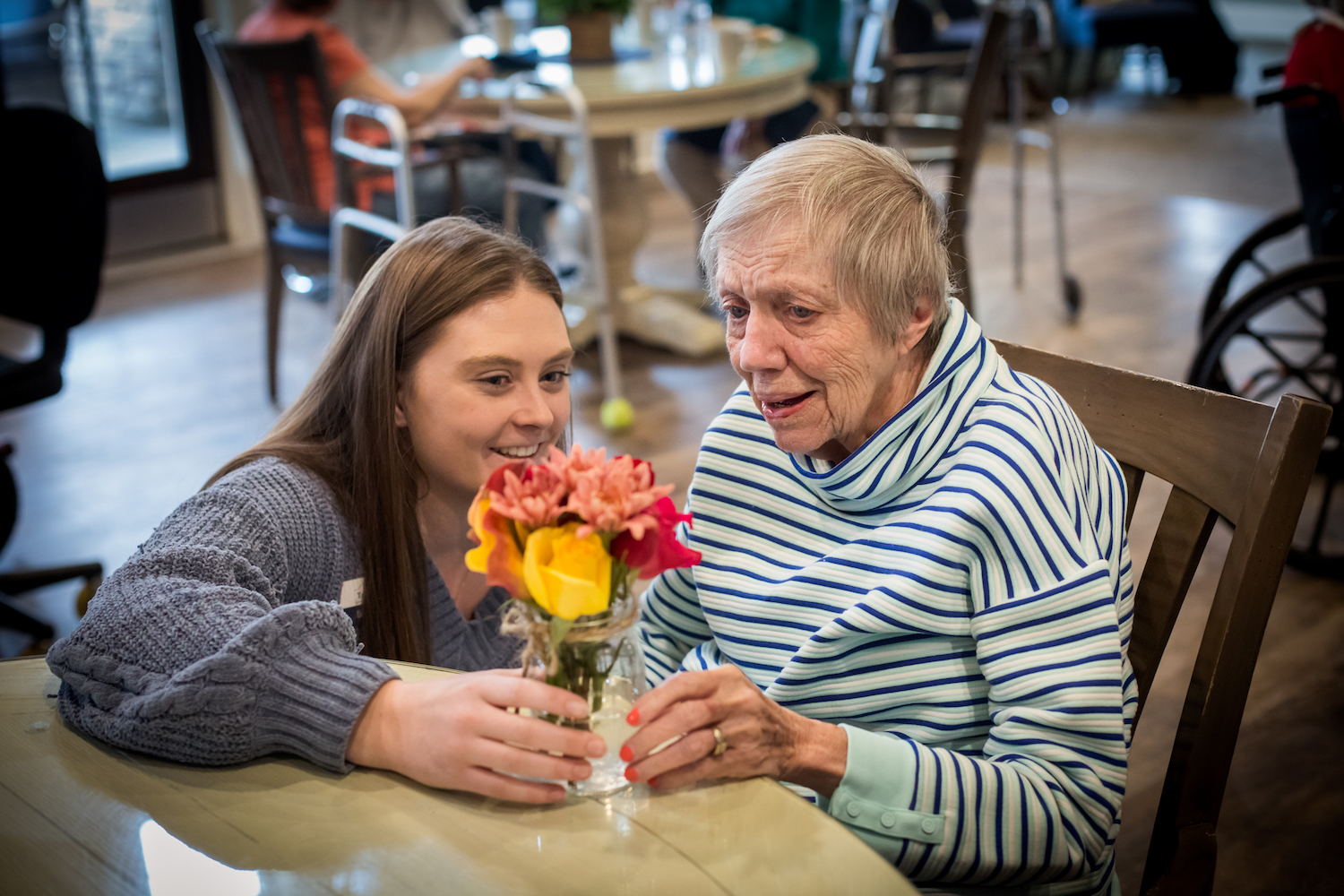 A woman delivering flowers to an elderly woman