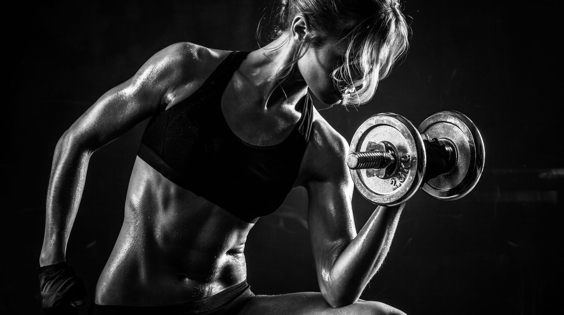 Black and white photo  of an athletic woman lifting a dumbbell