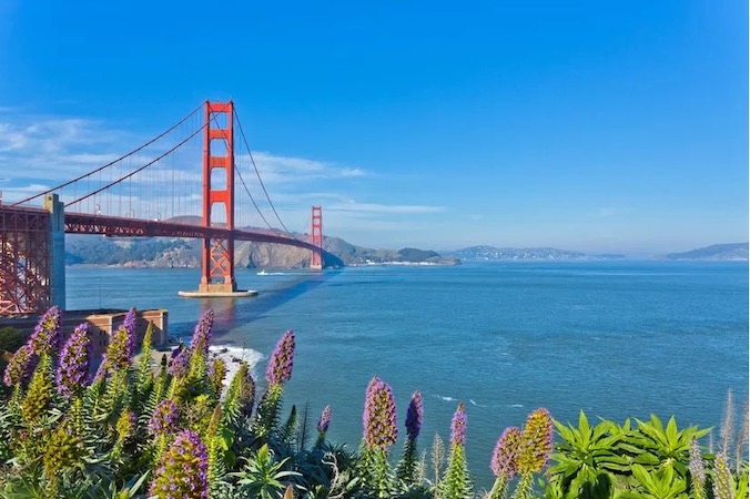 Towers of the Golden Gate Bridge raise from the blue waters of the bay