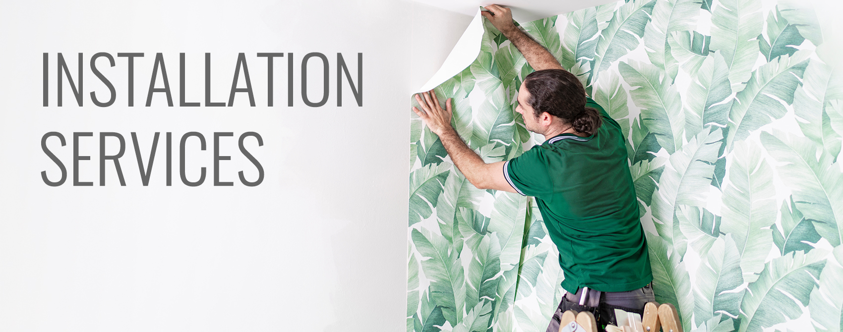 A man installing a leaf pattern mural