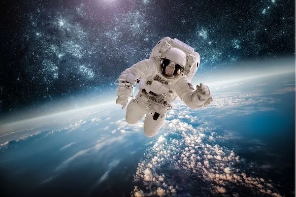 An astronaut floats in space with Earth below