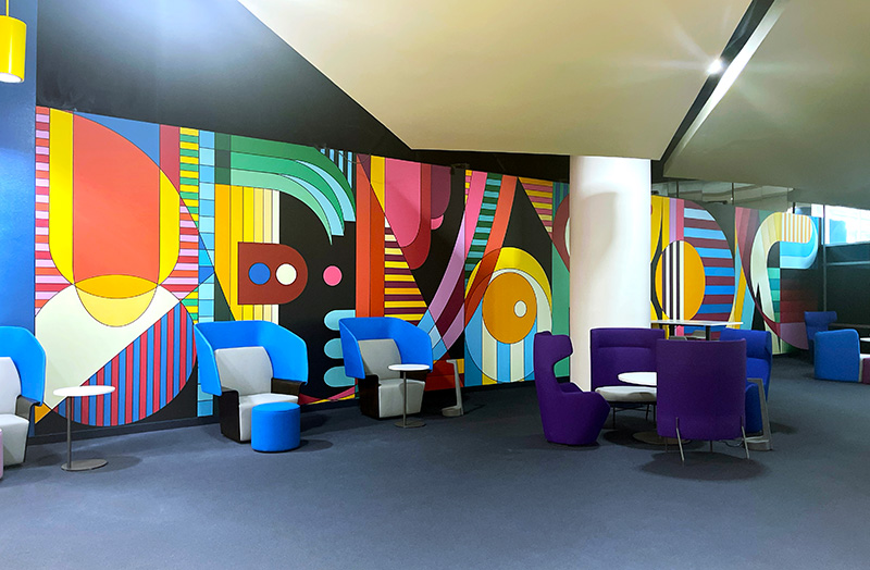 Colorful geometric wall mural with the word Florida hidden inside installed in a office lunch area